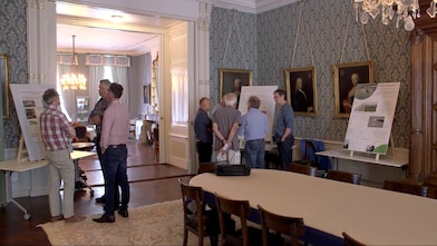 Heren staan te praten bij presentatieborden in klassieke kamer