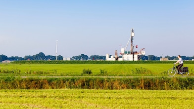 Groen weiland met fietser op fiets pad, in de verte een winningslocatie