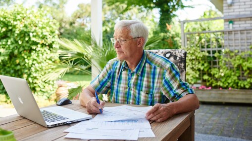 Meneer achter een laptop met papieren voor zich