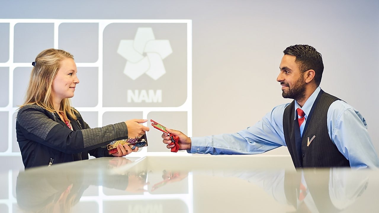 Mannelijke beveiligingsbeambte reikt bezoekerspas uit aan vrouw