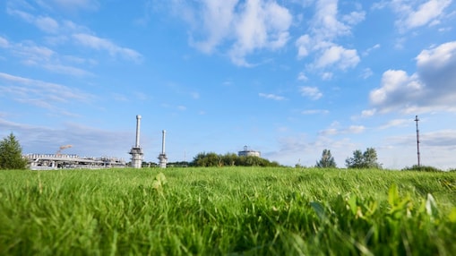 Blauwe lucht en groen gras met in de verte een gaswinningslocatie