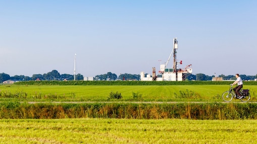 Groen weiland met fietser op fiets pad, in de verte een winningslocatie