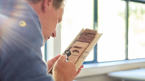 Man bestudeert grondmonsters met een loep