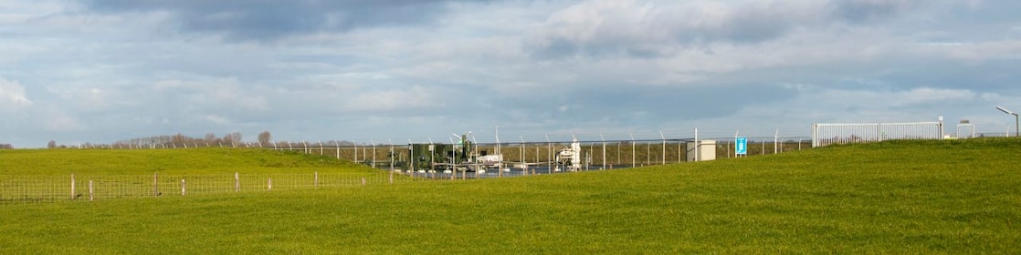 Groene weilanden met daarin een gaswinningslocatie onder een blauwe lucht
