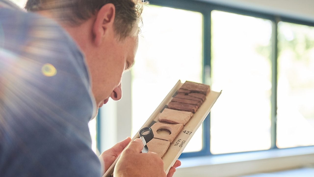 Man bestudeert grondmonsters met een loep