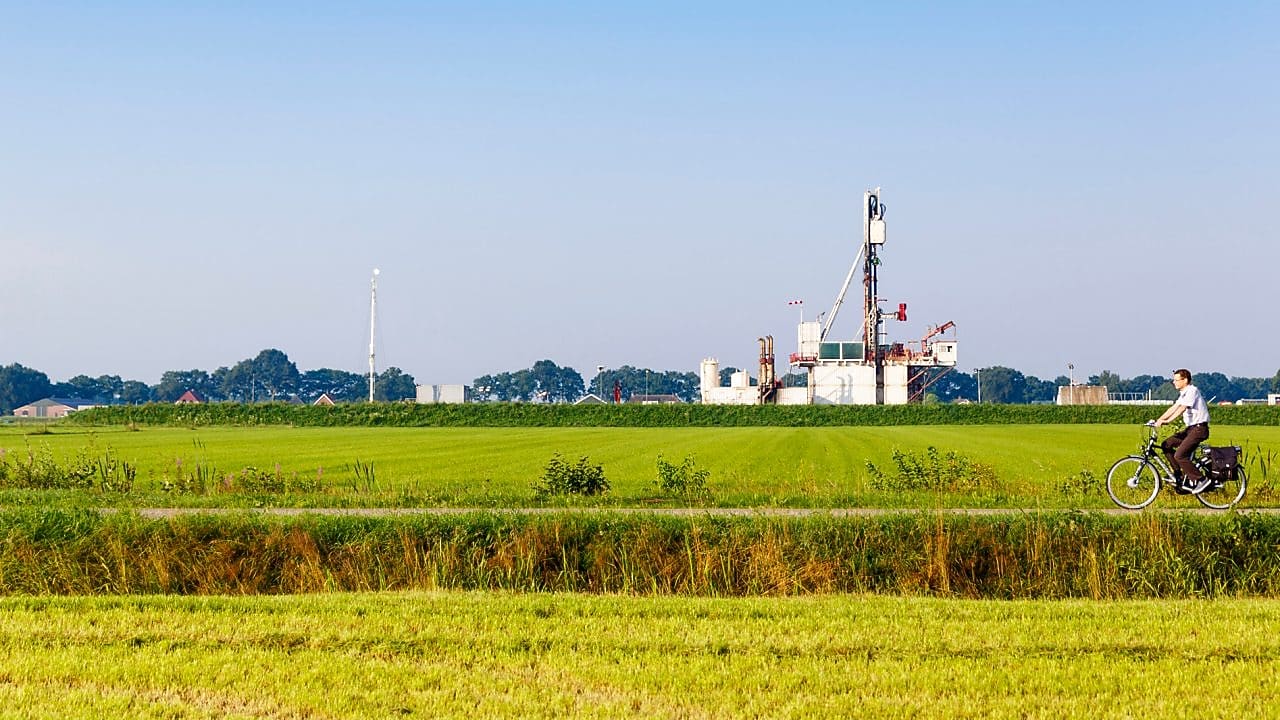 Groen weiland met fietser op fiets pad, in de verte een winningslocatie