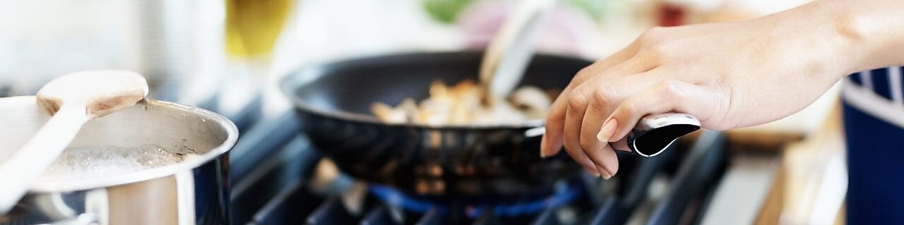 Twee pannen op een fornuis waaraan gekookt wordt