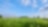 Blauwe lucht en groen gras met in de verte een gaswinningslocatie