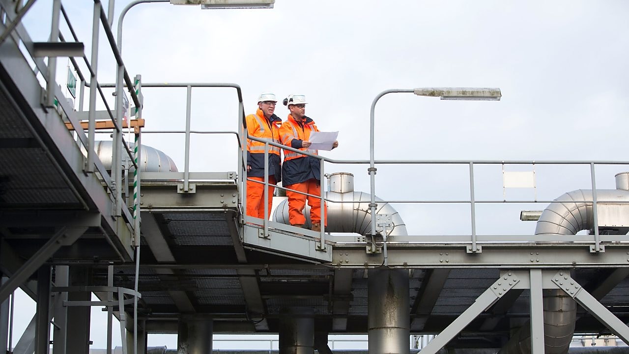 Werklui in oranje overalls kijken op een kaart