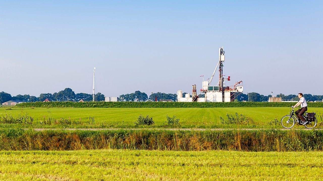 Groen weiland met fietser op fiets pad, in de verte een winningslocatie