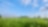 Blauwe lucht en groen gras met in de verte een gaswinningslocatie