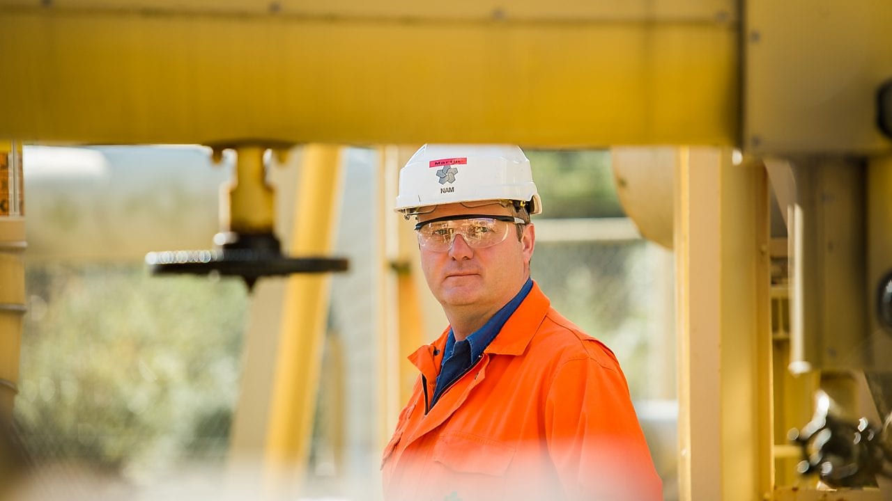 Medewerker op achtergrond achter een geel stelsel van buizen