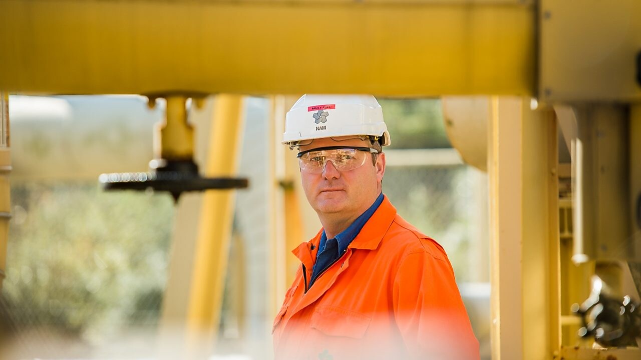Medewerker op achtergrond achter een geel stelsel van buizen