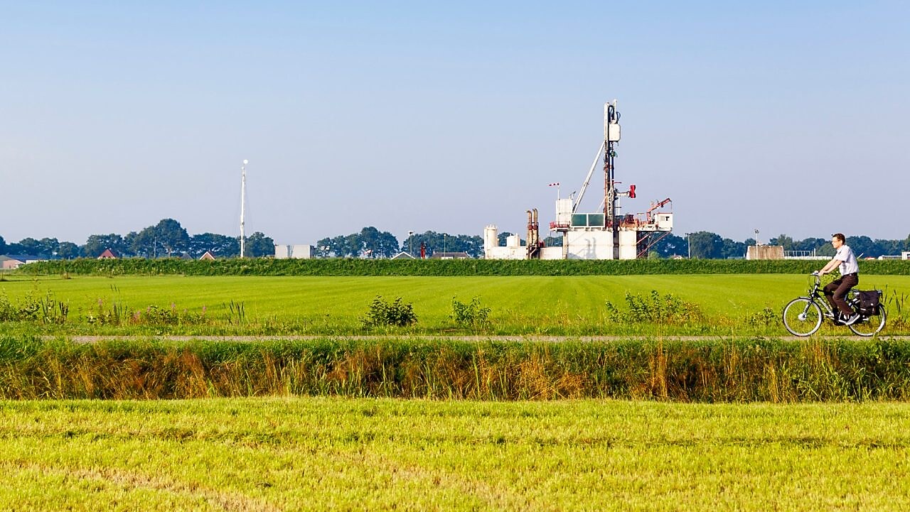 Groen weiland met fietser op fiets pad, in de verte een winningslocatie