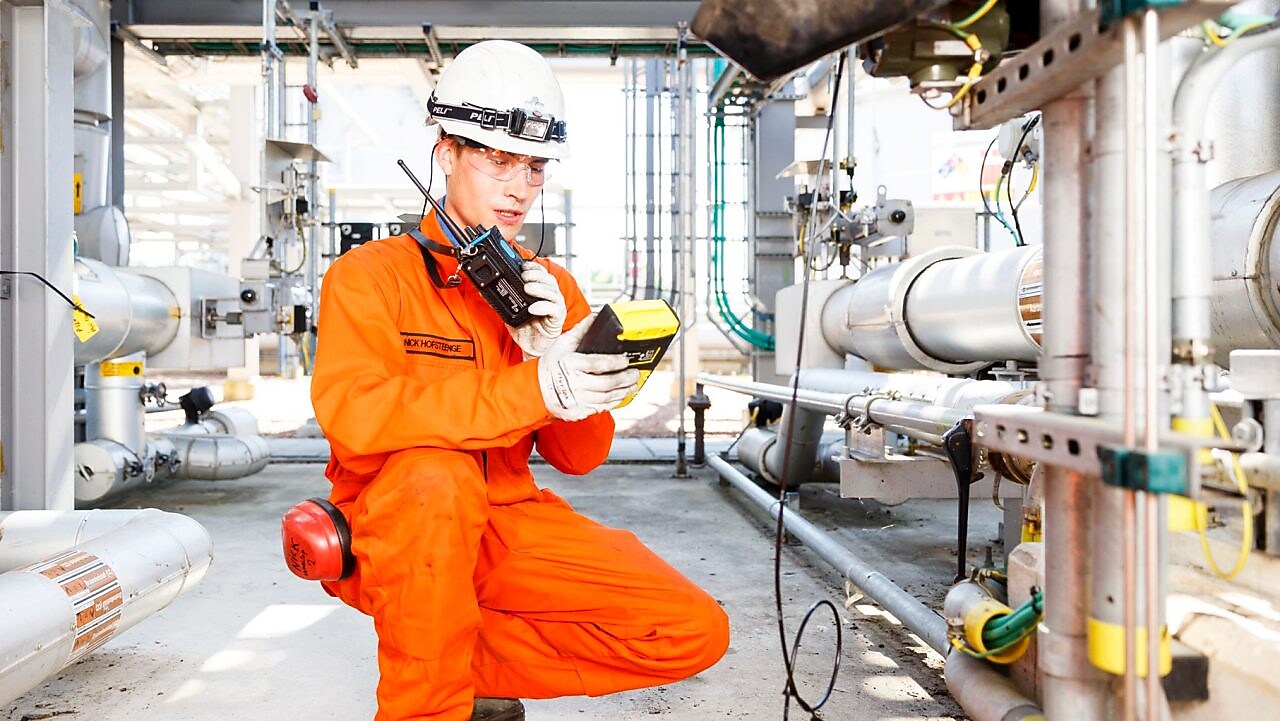 Man in oranje overall bestudeert een meter