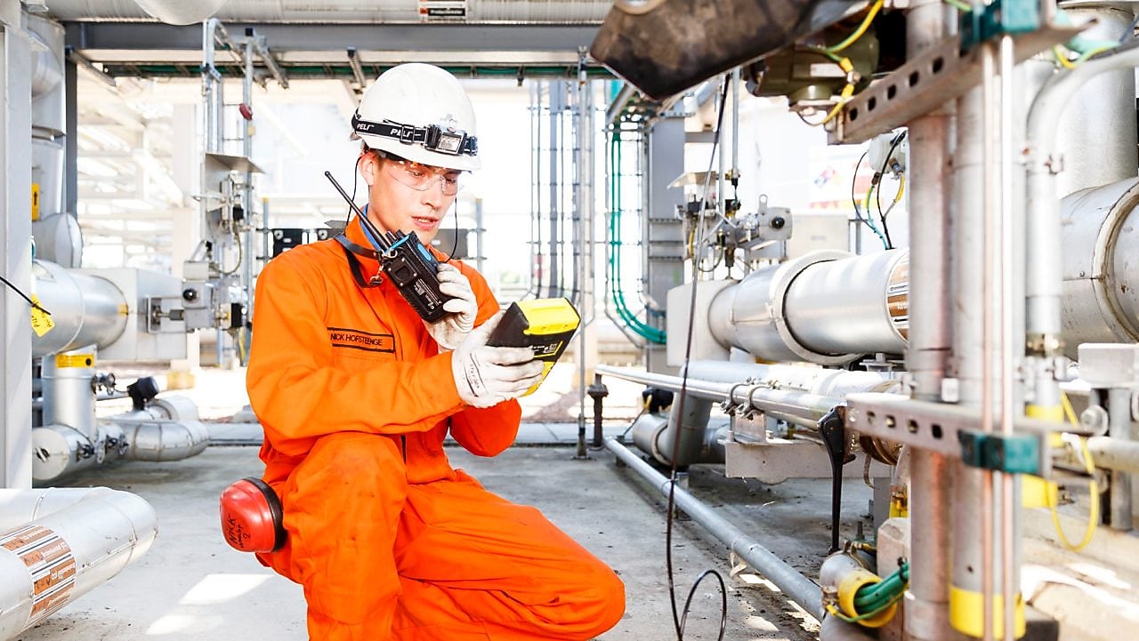 Man in oranje overall bestudeert een meter