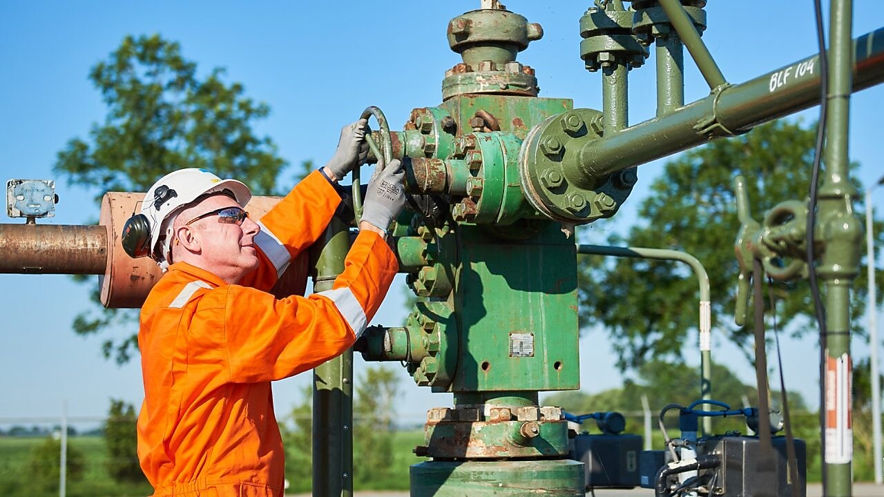 Man in oranje overall bedient een machine
