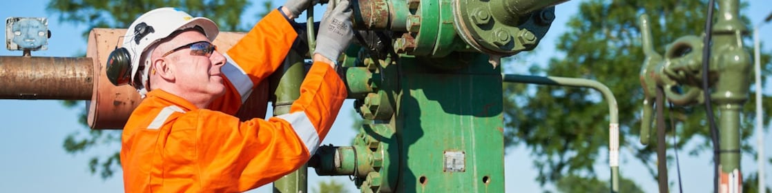 Man in oranje overall bedient een machine