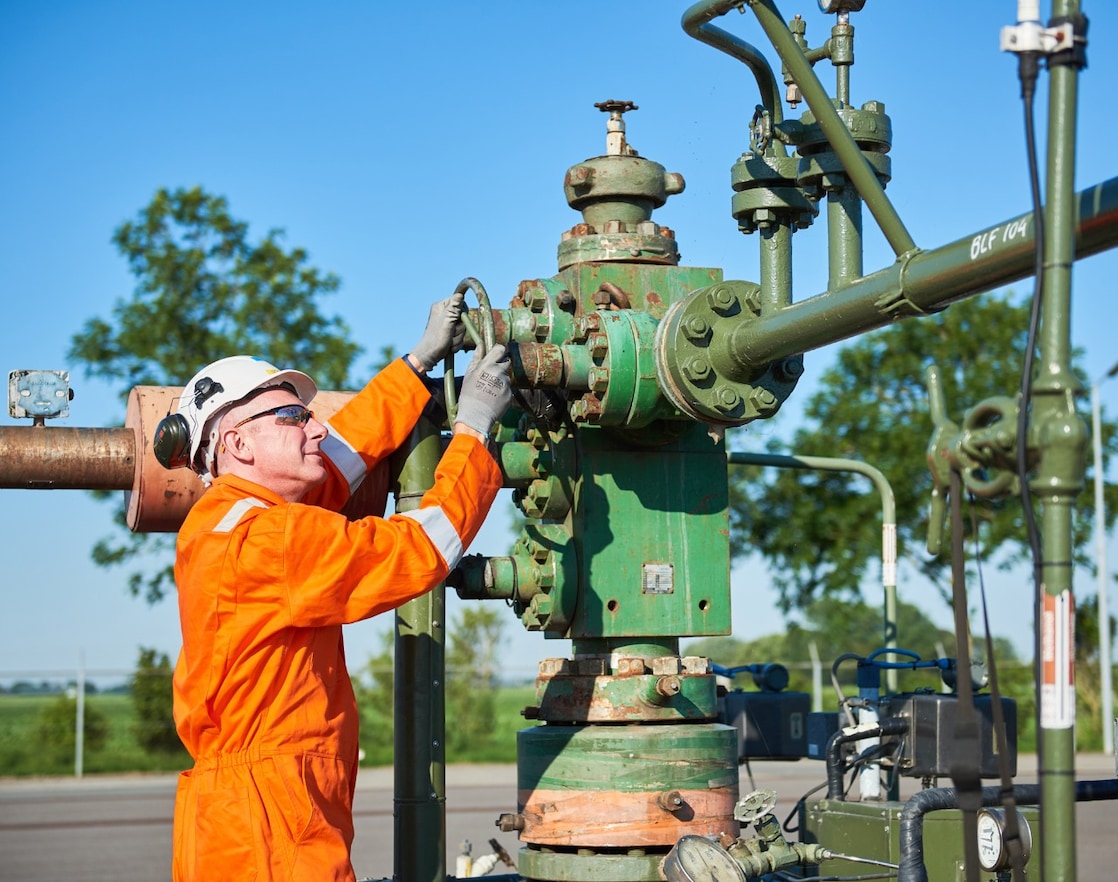 Man in oranje overall bedient een machine