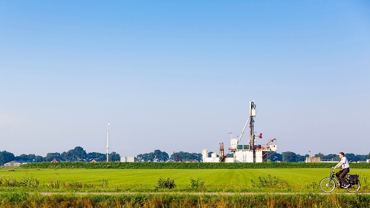 Groen weiland met fietser op fiets pad, in de verte een winningslocatie