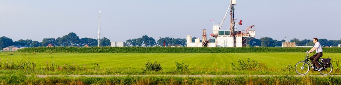 Groen weiland met fietser op fiets pad, in de verte een winningslocatie