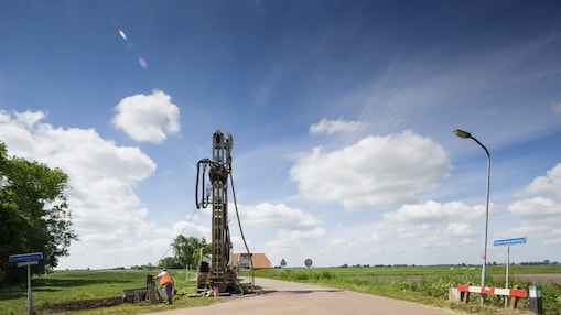 Een machine langs de kant van de weg met een medewerker ernaast