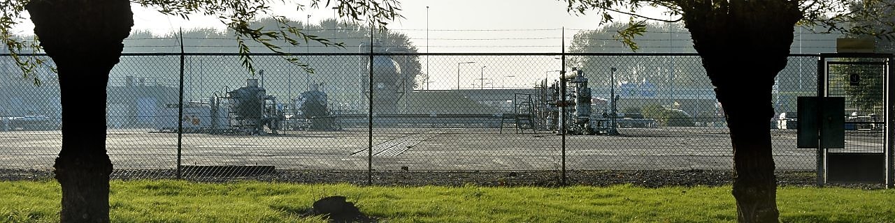 Twee bomen, met daarachter een gasproductie locatie