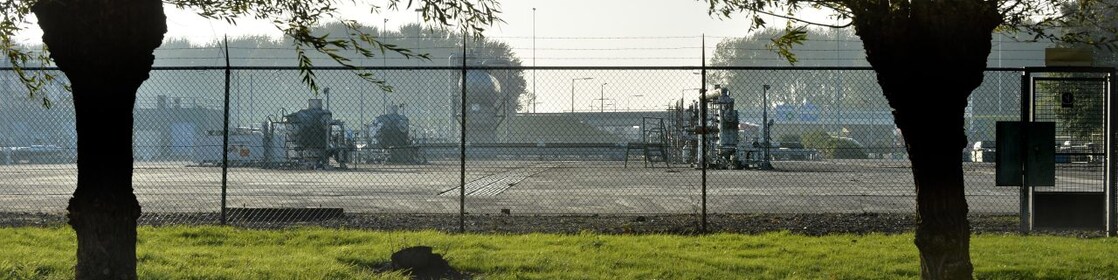 Twee bomen, met daarachter een gasproductie locatie