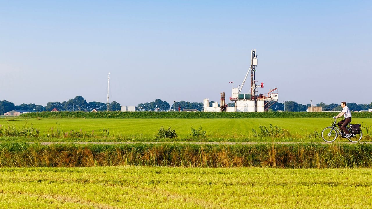 Groen weiland met fietser op fiets pad, in de verte een winningslocatie