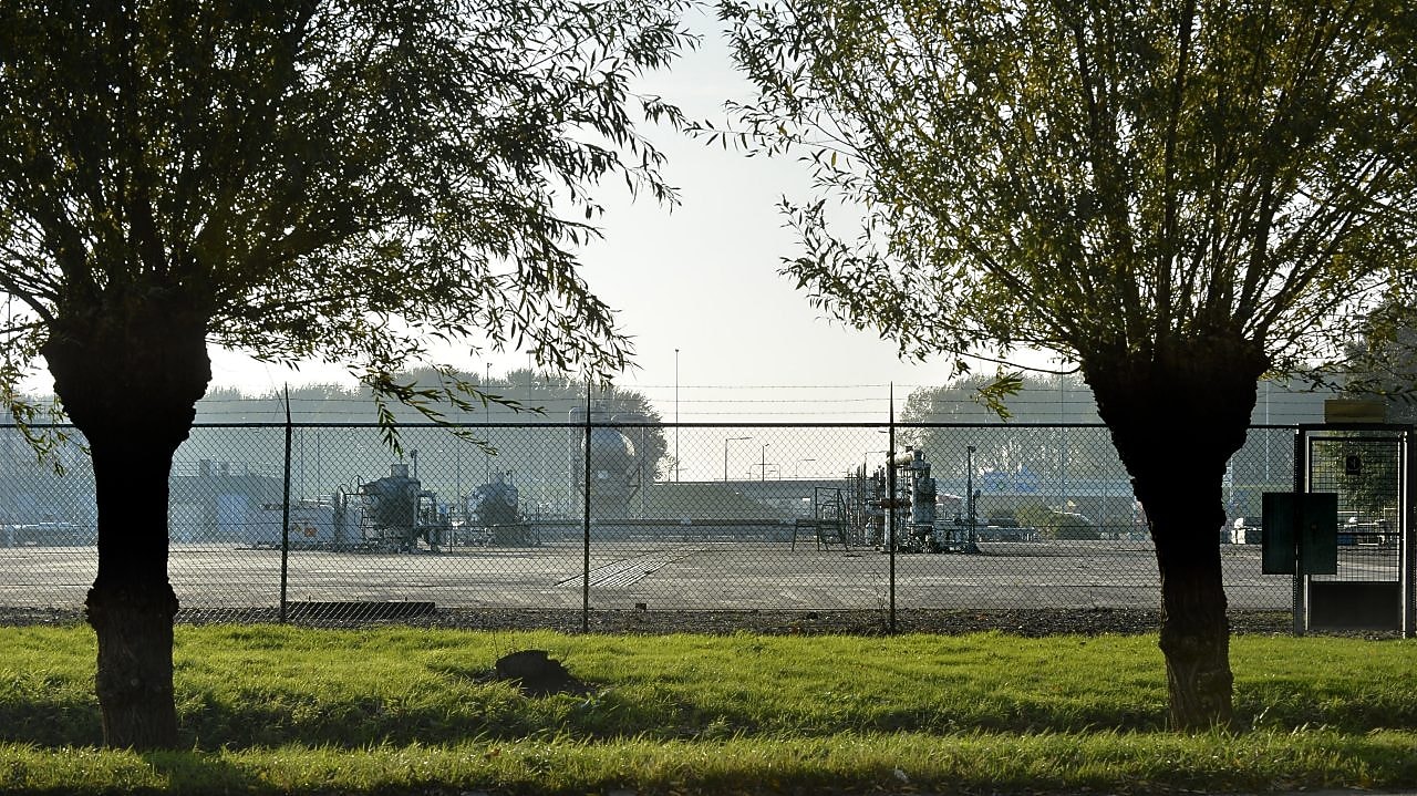 Twee bomen, met daarachter een gasproductie locatie