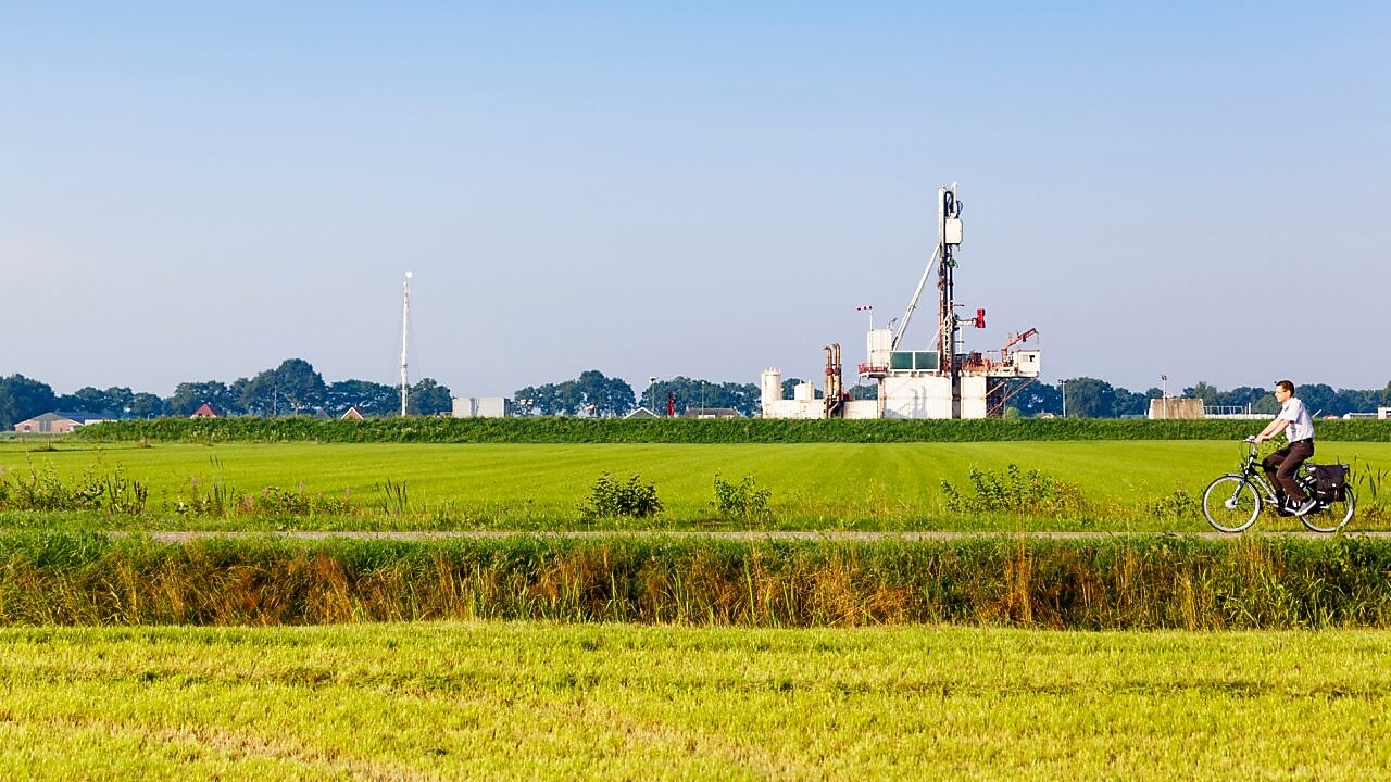 Groen weiland met fietser op fiets pad, in de verte een winningslocatie