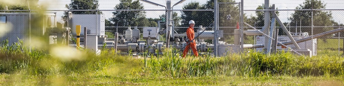 Man met oranje overall achter een hek