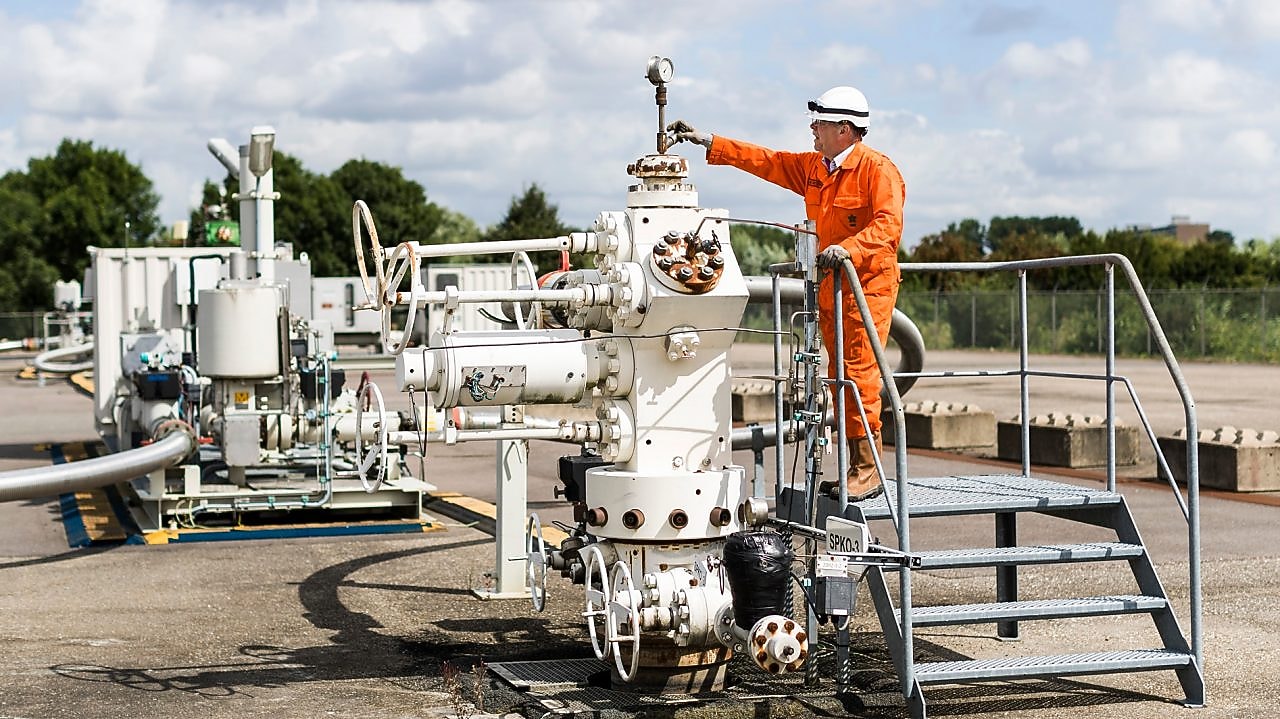 Man in oranje overall op een machine
