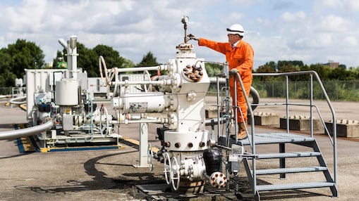 Man in oranje overall op een machine