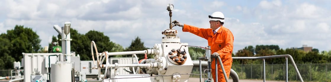 Man in oranje overall op een machine