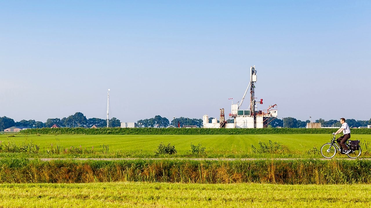 Groen weiland met fietser op fiets pad, in de verte een winningslocatie