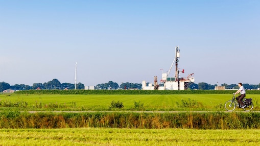 Groen weiland met fietser op fiets pad, in de verte een winningslocatie