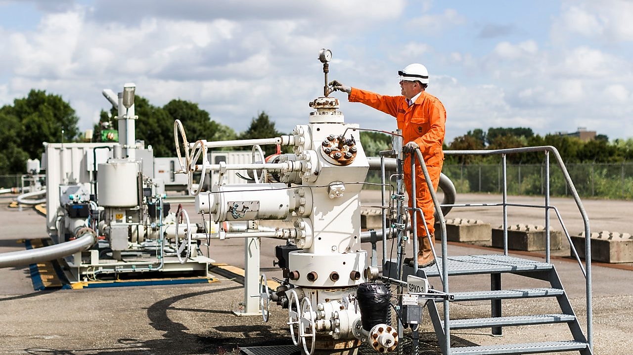 Man in oranje overall op een machine