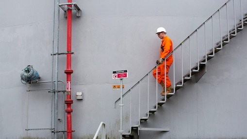 Medewerker in oranje overall loopt een ttrap af met zijn hand aan de leuning