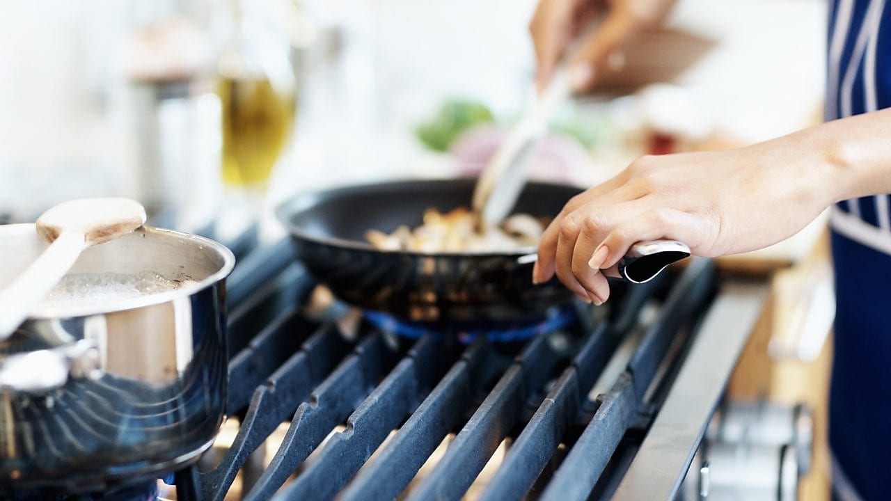 Twee pannen op een fornuis waaraan gekookt wordt