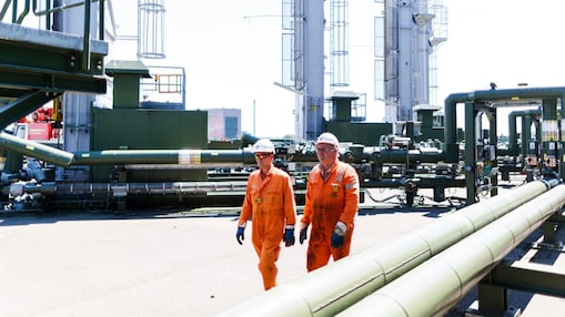 Twee mannen met oranje overall lopen over een winningslocatie