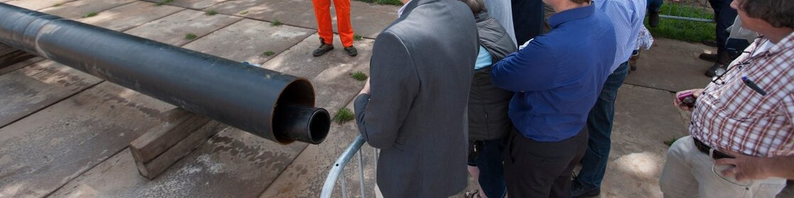 Man in oranje overall geeft uitleg aan groep toehoorders