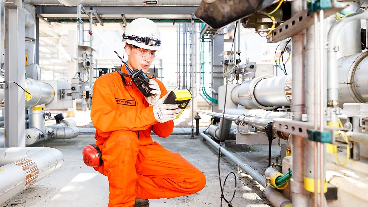 Man in oranje overall bestudeert een meter