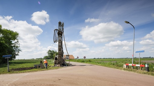 Een machine langs de kant van de weg met een medewerker ernaast