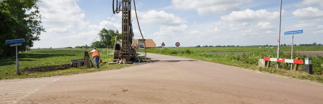 Een machine langs de kant van de weg met een medewerker ernaast