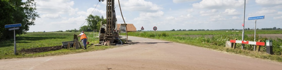 Een machine langs de kant van de weg met een medewerker ernaast