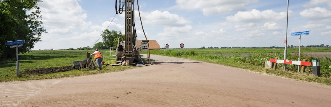 Een machine langs de kant van de weg met een medewerker ernaast