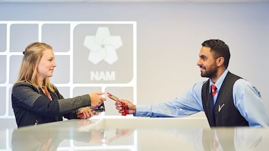 Mannelijke beveiligingsbeambte reikt bezoekerspas uit aan vrouw