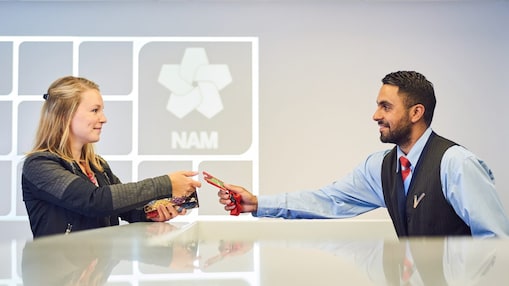 Mannelijke beveiligingsbeambte reikt bezoekerspas uit aan vrouw