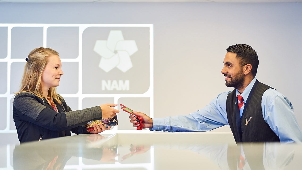 Mannelijke beveiligingsbeambte reikt bezoekerspas uit aan vrouw